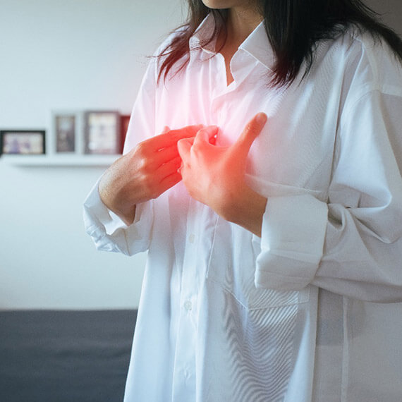 Mujer con camisa blanca, tocando su pecho para diagnosticar esofagitis y reflujo gastroesofágico, padecimientos tratados por la Dra. Irasema Salgado Falcón